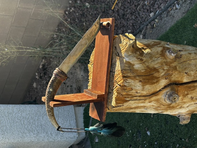 Handmade knife with an antler handle displayed on a wooden stand