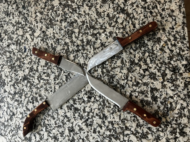 Four handmade knives crossed over a stone countertop